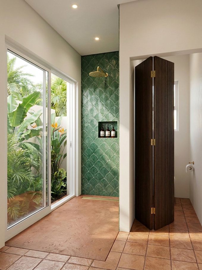 A garden shower finished in palm-leaf tilework, opening onto a quiet green corner.